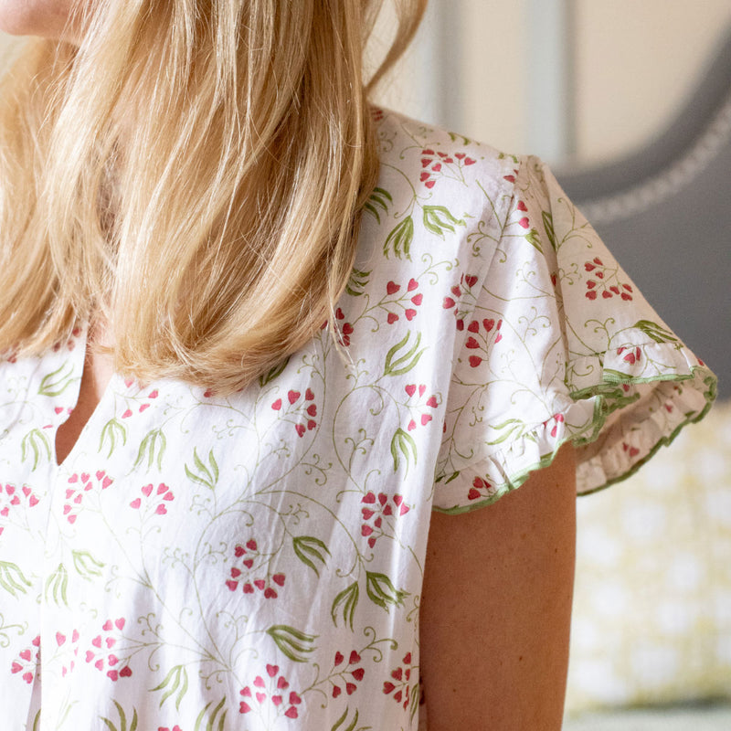 Close-up of a woman wearing a green cap sleeve nightie with a floral blockprint design.