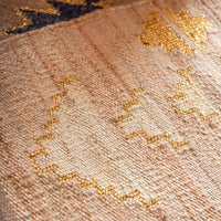 Close-up of a textured jute with gold embroidery on a beige background