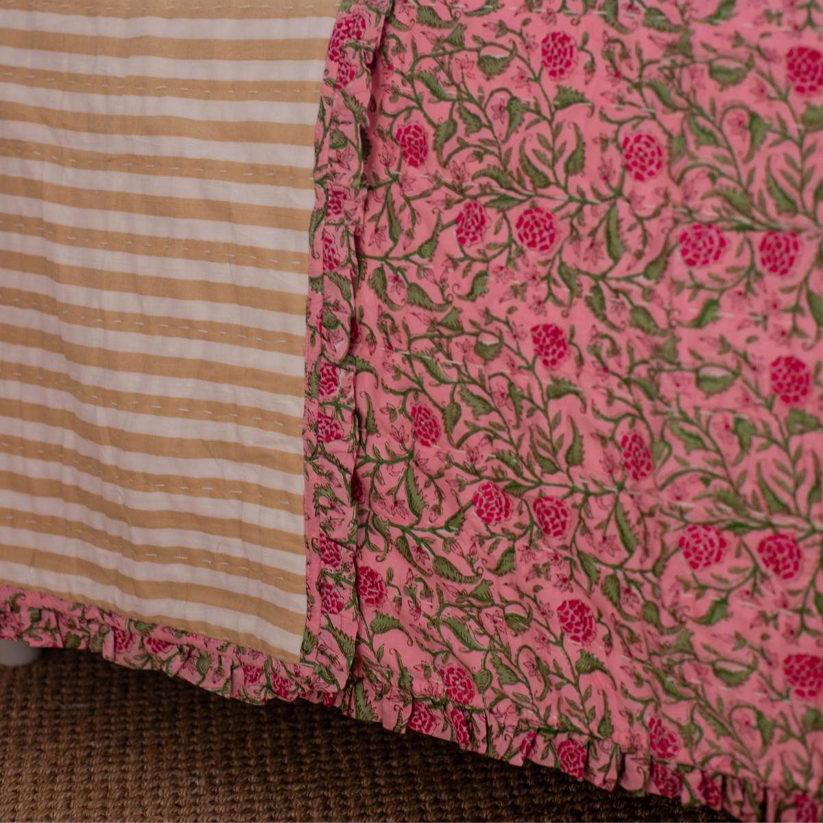 Close-up of a pink floral fabric with a striped pattern in the corner