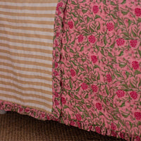 Close-up of a pink floral fabric with a striped pattern in the corner