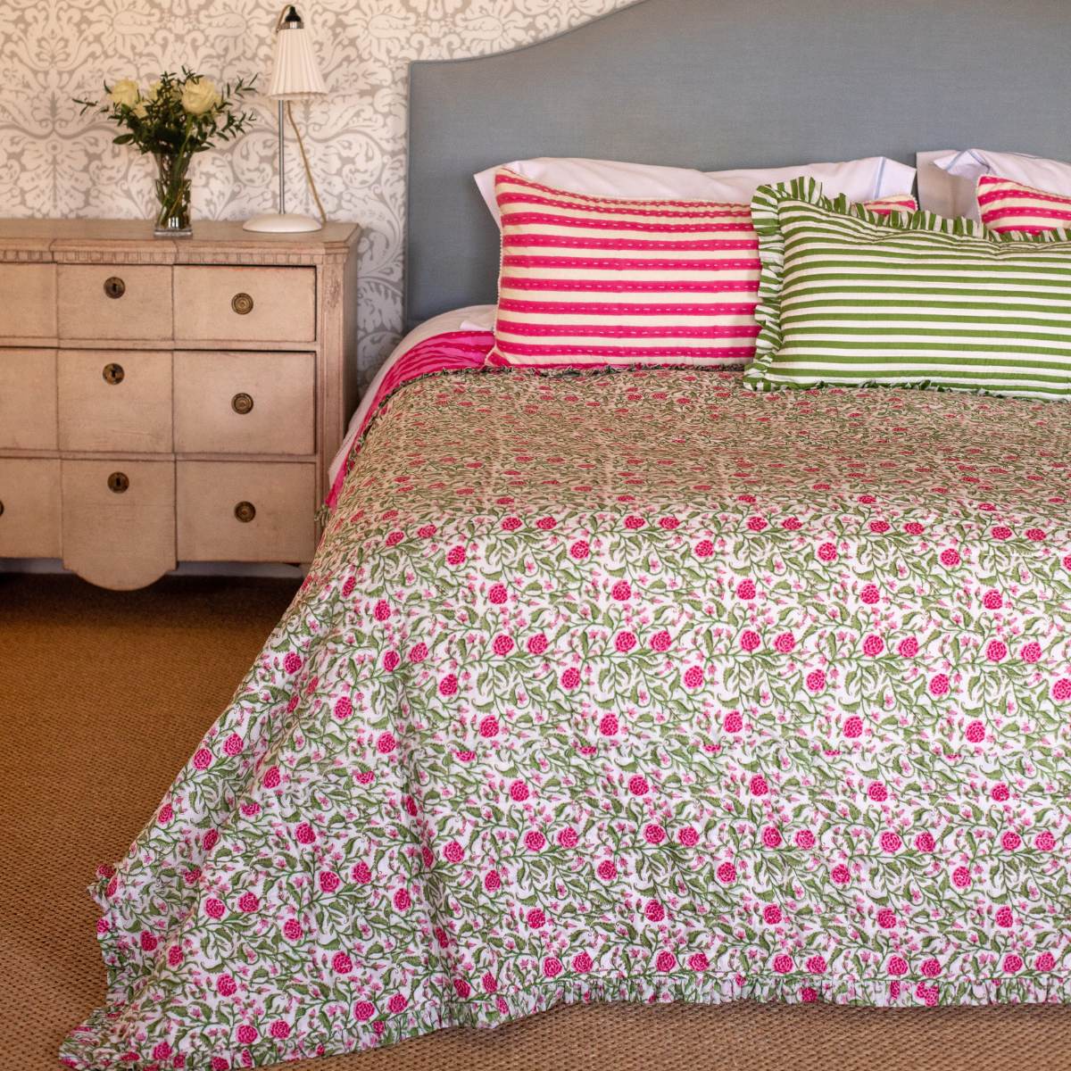 Bed with floral bedding and striped pillows in a bedroom setting.
