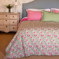 Bed with floral bedding and striped pillows in a bedroom setting.