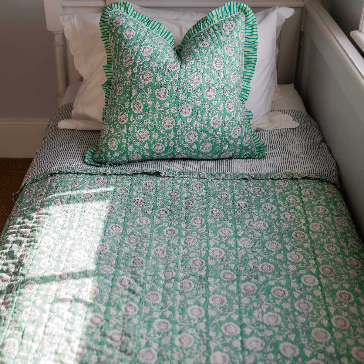Bed with green floral bedding and pillow