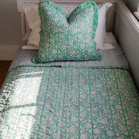 Bed with green floral bedding and pillow
