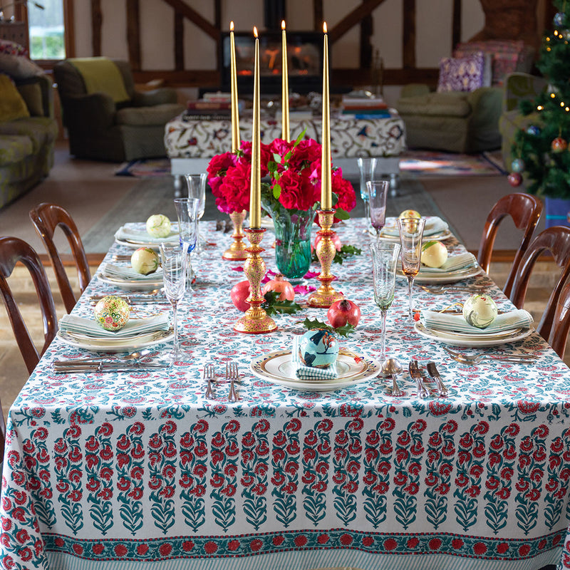 Dining table set for a meal with floral tablecloth, candles, and decorative items.